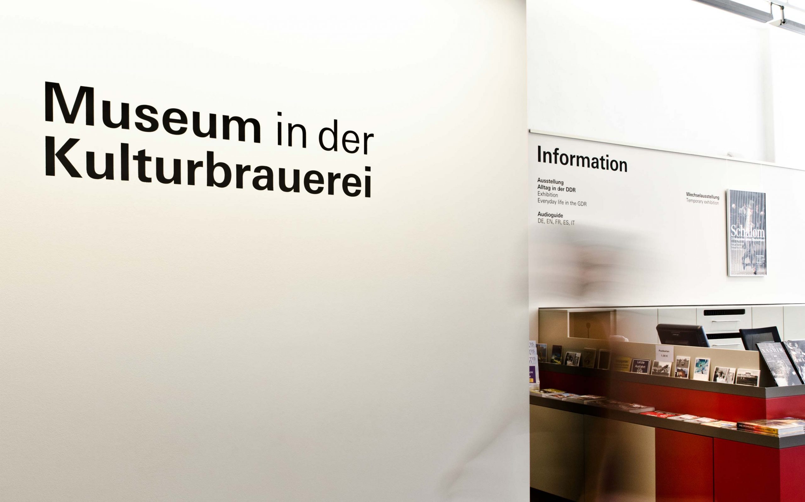 Eingangsbereich des Museums in der Kulturbrauerei mit Wandbeschriftung (Schablonierung), im Hintergrund die Informationstheke. Elemente: Schrift (Univers Regular und Univers Bold)